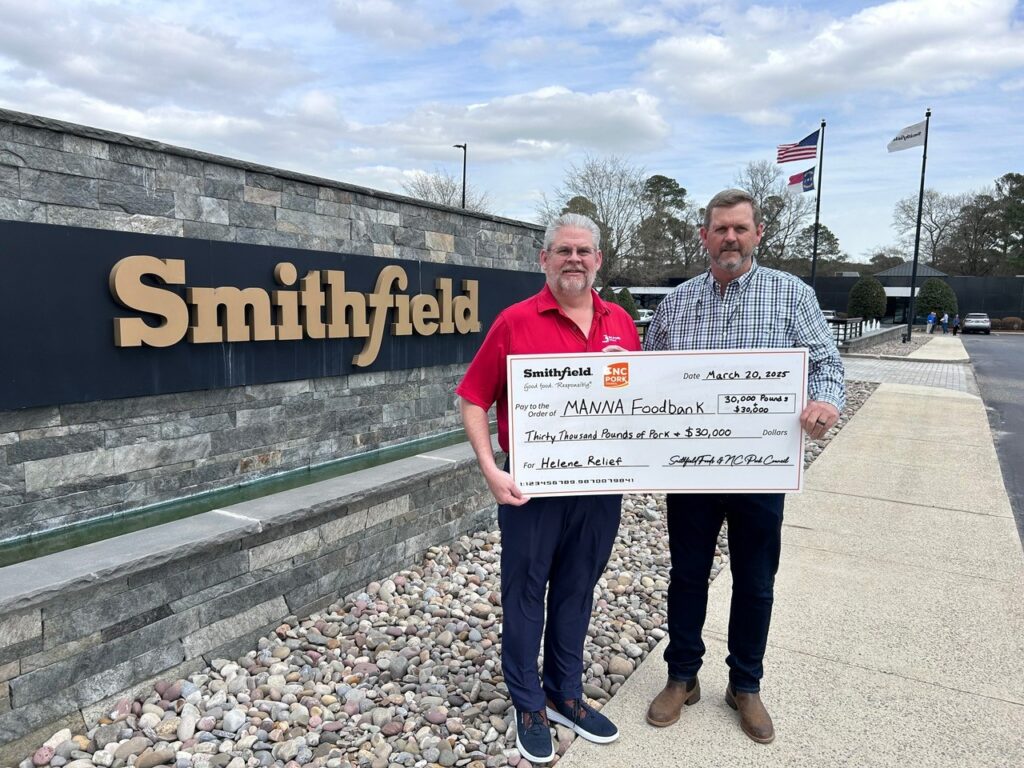 two men holding check in front of smithfield foods signage